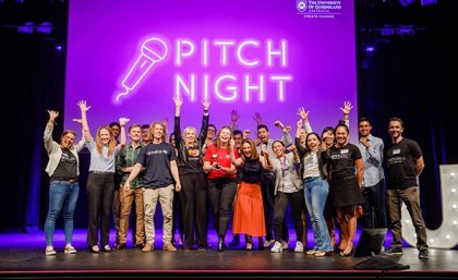 Group shot of Pitch Night finalists on stage with Ashley Hanger, the winner, in the middle holding the trophy